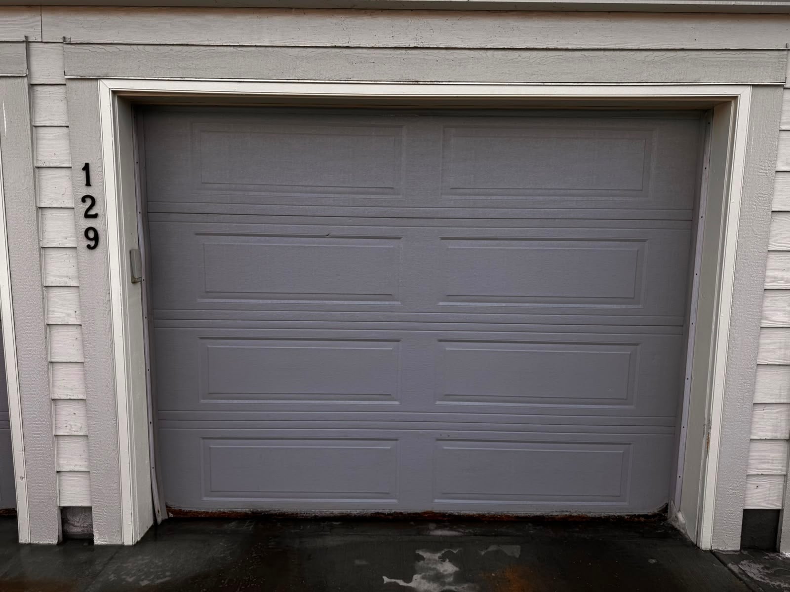 Installed gray paneled garage door on a white home