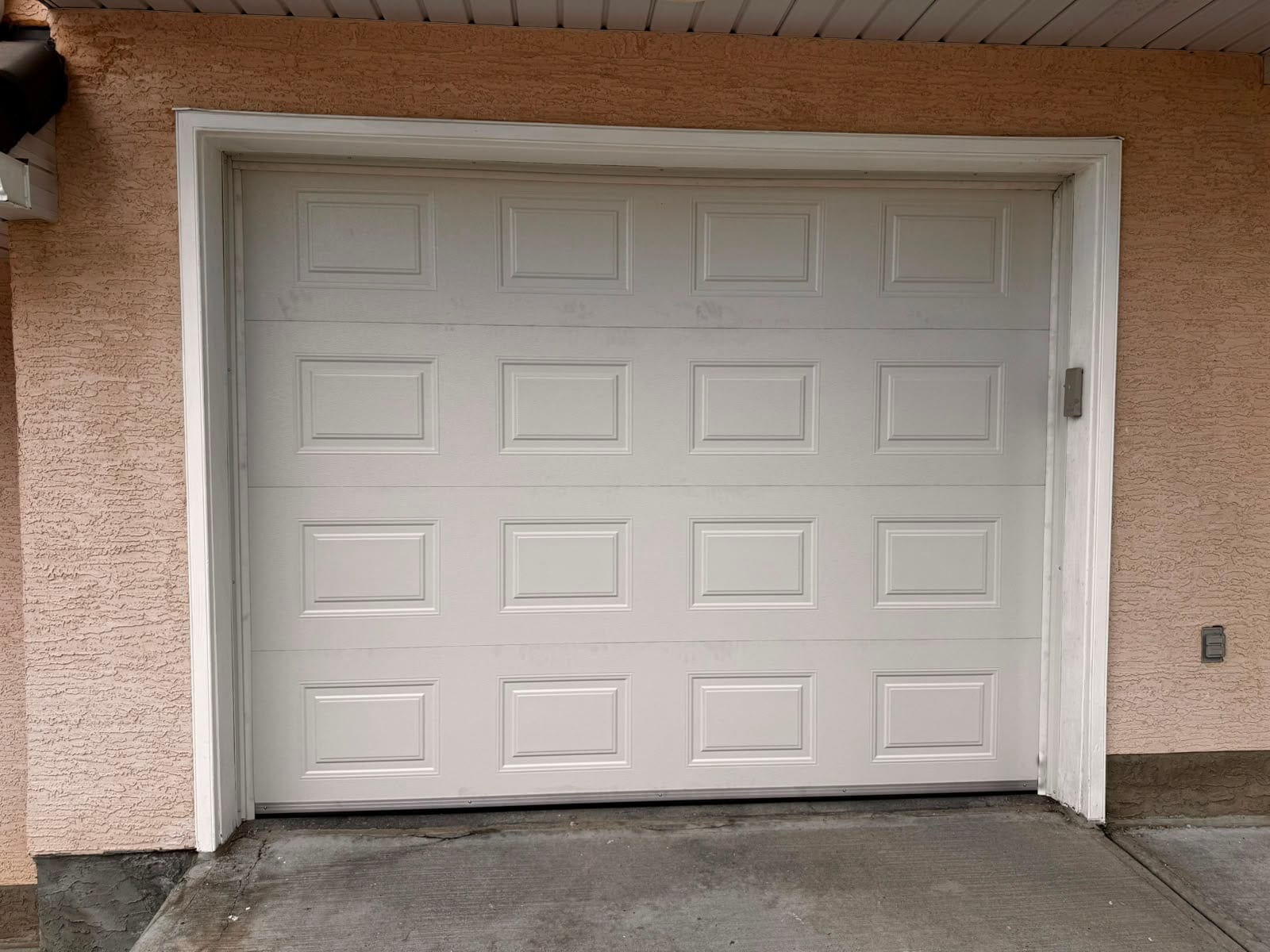 Installed white paneled garage door on a stucco home