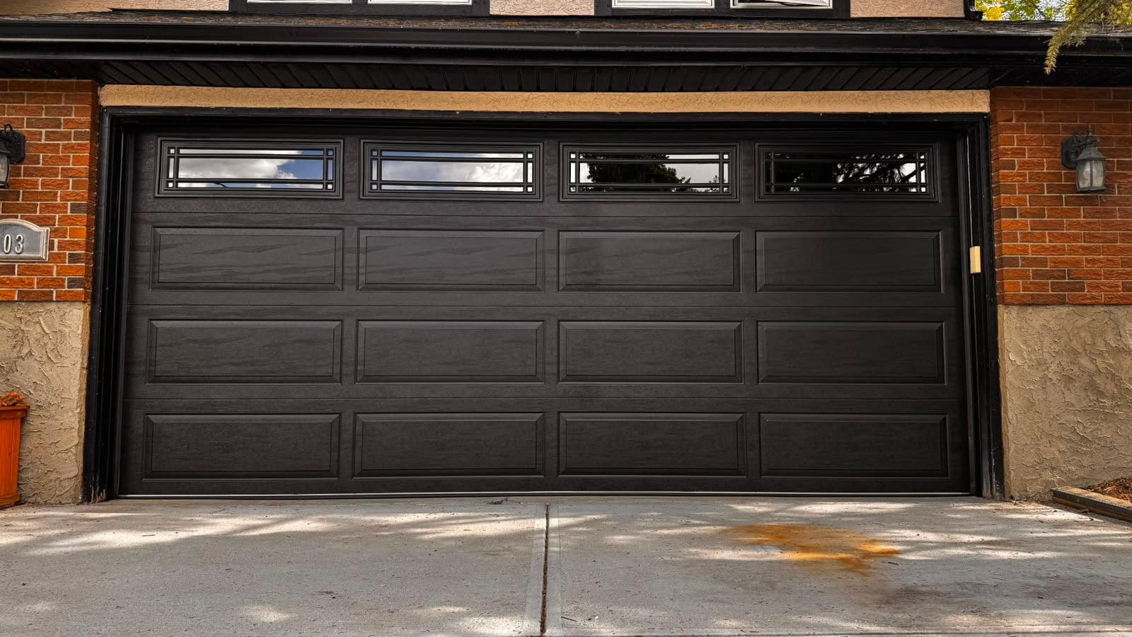 Installed black wood-grain garage door with glass panels