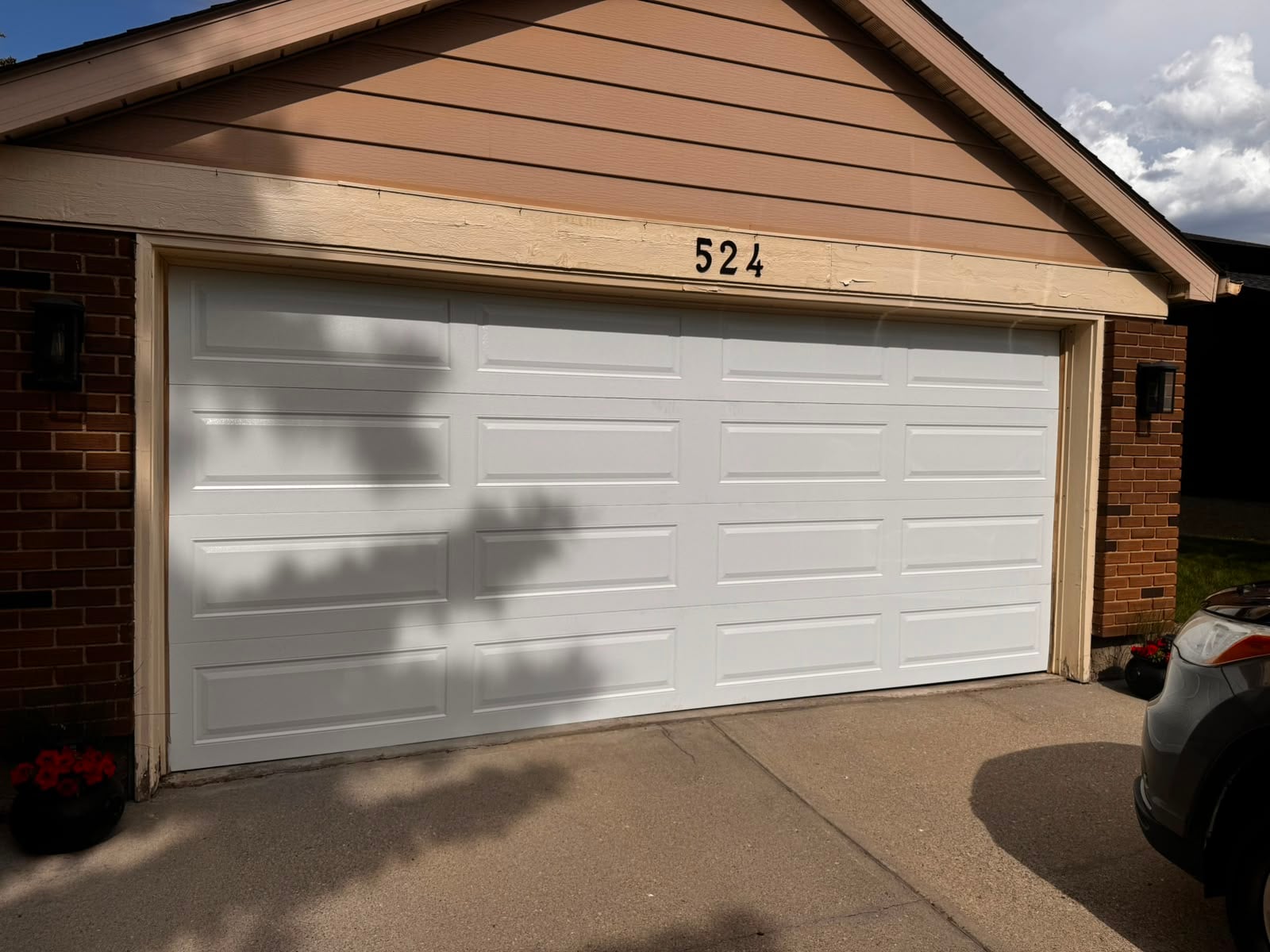 Installed white double-car garage door on a brick home